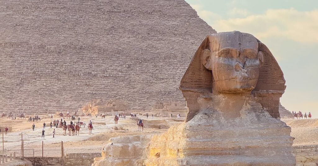 Ancient Great Sphinx with Pyramid of Giza in the background, captured at sunset.